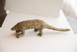 Vintage African pangolin sculpture in profile showing its textured, scaled body and aged patina.