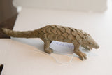 Side profile view of the vintage African pangolin sculpture with its inventory tag.