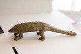 The weathered surface and segmented scales of a vintage African pangolin sculpture.