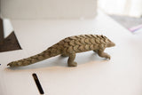 Full profile of the vintage pangolin sculpture showing its long, scaled body.