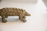Angled profile of the vintage pangolin sculpture showing textured scales and claws.