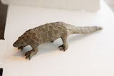 Three-quarter view of the vintage pangolin sculpture's textured, scaled body.