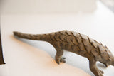 A side view of the handmade African pangolin sculpture highlighting its long, scaled body.