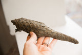 Vintage pangolin sculpture held in hand to display its textured scales and size.