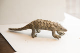Side profile view of the vintage African pangolin sculpture's textured, scaled body.