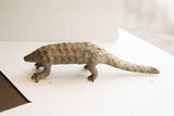 Side view of a collectible African pangolin statue with a weathered, scaly texture.