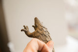 Underside view of the vintage pangolin sculpture's head, showing carved scales and paw.