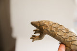 Angled close-up of the pangolin sculpture's head and textured, handmade scales.