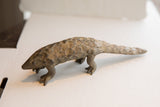 Vintage African pangolin sculpture with aged patina and defined, scaly texture.