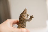 Side profile of the vintage pangolin sculpture, showing its textured head and reaching claw.