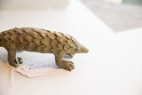 Side profile of a vintage pangolin sculpture with earthy, textured scales.