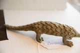 Side profile view of the vintage African pangolin sculpture with its inventory tag.