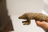 Vintage African pangolin sculpture held in hand, displaying its profile and scaled texture.
