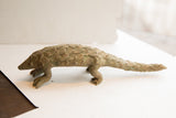 Side profile of the vintage pangolin sculpture highlighting its textured, scaled body.