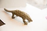 The long body and textured scales of a vintage handmade pangolin sculpture.