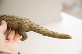 Textured overlapping scales along the vintage pangolin sculpture's body and tapering tail.