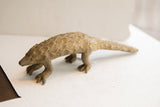 Side view of a vintage pangolin sculpture showing its earthy, textured scales.