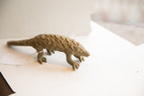 Vintage African pangolin sculpture showing its full form and textured, scaled body.