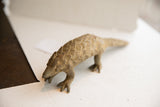 Angled side view of the vintage pangolin sculpture showing its earthy, textured scales.