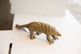 The handmade, earthy-toned scales on the body of the vintage pangolin sculpture.