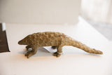 Vintage pangolin sculpture seen in profile, highlighting its elongated body and scaly texture.