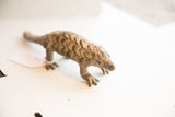 Three-quarters view of a collectible pangolin figure with rustic, textured scales.