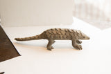 Profile view of the handmade pangolin sculpture detailing its textured scales and form.