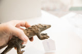 Hand holding the vintage African pangolin sculpture, showing its textured, scaled profile.