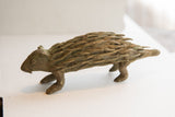 Three-quarter view of the handmade porcupine sculpture showing its rustic, aged patina.