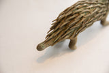The short, scored tail and textured, patinated quills of the vintage porcupine sculpture.