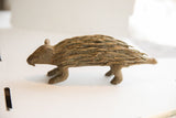 Side profile view of the vintage African porcupine sculpture's carved, textured body.