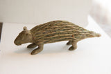 Side profile of the handmade African porcupine sculpture showing its textured, patinated body.
