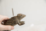 Profile view of the handmade porcupine sculpture's head showing its weathered, earthy texture.