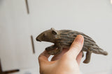 Vintage porcupine sculpture held to show its side profile and hand-carved texture.