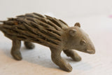 Close-up view of the vintage porcupine sculpture's head with simple, carved features.