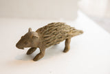 Side profile of a vintage African porcupine sculpture showing its rustic handmade texture.