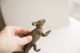 Hand holding vintage African porcupine sculpture, showcasing its ridged back and uplifted head.