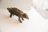 Profile view of a vintage handmade African porcupine sculpture showing its carved quills.