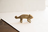 Side view of a vintage chameleon figurine with rustic, handmade texture and a curled tail.