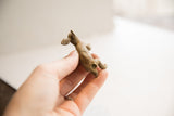 A hand holds the small African rabbit figurine, showing the rustic texture of its underside.