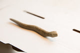 Angled profile of a handmade African snake figurine showing its textured, slithering form.