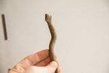 In-hand view showing the undulating shape and aged texture of the snake figurine.