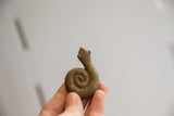 Vintage African snake figurine with a rustic, coiled body held to show scale.