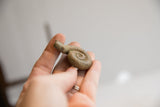 A small, handmade African snake figurine held to show its petite scale and texture.