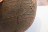 Close-up of the incised geometric designs and aged texture on the hand-carved wooden bowl.