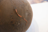 An antique strap repair on the aged, textured surface of the wooden bowl.
