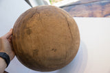 Hand holding the antique wooden bowl, revealing its aged character and visible cracks.