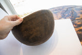 Textured dark wood surface and rim of an antique African hand-carved bowl.