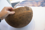 Hand holds aged African wooden bowl, incised with geometric patterns and an antique repair patch.