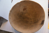 Aged interior of antique carved wooden bowl, showing deep wood grain, cracks, and metal repair.